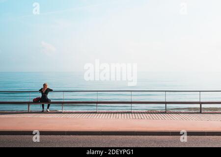 Blick von hinten auf EINE blonde Frau, die vorne sitzt Des Meeres Stockfoto