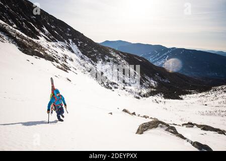 Kletterer den Berg mit Werkzeugen und Skiern im Weiß aufsteigen Berge Stockfoto