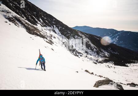 Kletterer den Berg mit Werkzeugen und Skiern im Weiß aufsteigen Berge Stockfoto