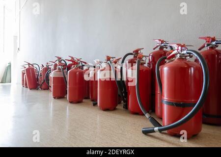 Ein Haufen abgelaufener Feuerlöscher auf dem Boden neben der Wand. Erneuerung der Feuerlöscher für Unternehmen. Stockfoto