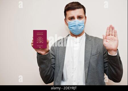 Europäischer Mann in formeller Kleidung und Gesichtsmaske, zeigen Spanien Pass mit Stop-Zeichen Hand. Coronavirus-Lockdown im europäischen Länderkonzept. Stockfoto