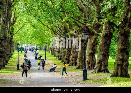 London, Großbritannien - 21. Juni 2018: Menschen in Alleerstraße Straße Weg in Green Park in Westminster mit Blick auf die Landschaft während grünen Sommertag mit Bänken Stockfoto