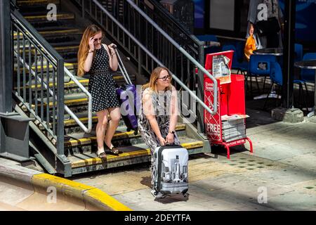 London, Großbritannien - 22. Juni 2018: Die Leute haben draußen mit Gepäcktaschen am Eingang der U-Bahn am Zeitungskiosk gecandiert Stockfoto