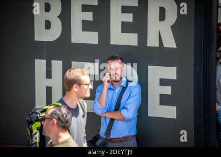 London, Großbritannien - 22. Juni 2018: Geschäftsmann Mann Menschen stehen an einer Wand des Gebäudes auf der Straße von Bar Pub mit Schild für Bier hier Stockfoto