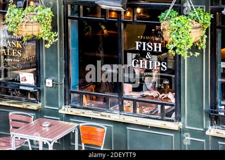 London, Großbritannien - 22. Juni 2018: Pommes Frites Fish Chips Restaurant Greene King Pub Taverne Bar Restaurant Schild auf Gebäude außen mit Menschen in sitt Stockfoto