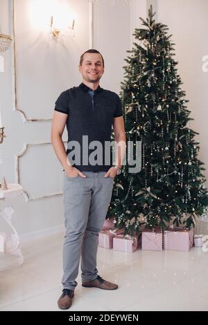 Fröhlicher Herr lächelt und steht in der Nähe von Weihnachtsbaum Stockfoto