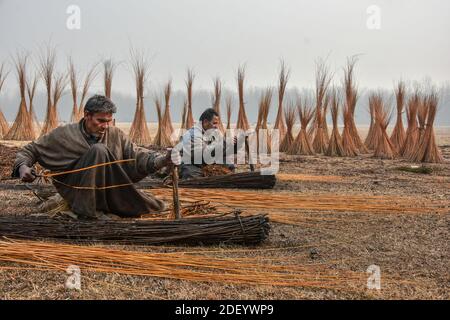 Srinagar, Indien. Dezember 2020. Kashmiri Männer bereiten Zweige vor, um "Kangris", (traditionelle Feuertöpfe) in Shlabugh Dorf des Bezirks Ganderbal ungefähr 22kms von Srinagar zu bilden.das Kangri ist ein traditioneller Feuertopf, der Leute während der strengen Wintermonate warm hält, wenn Temperatur bis zu so niedrig wie minus 20 abtaucht. Kangri ist aus Ton und Zweigen, in denen heiße Kohle gehalten wird. Kredit: SOPA Images Limited/Alamy Live Nachrichten Stockfoto