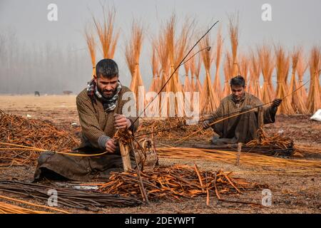 Srinagar, Indien. Dezember 2020. Kashmiri Männer bereiten Zweige vor, um "Kangris", (traditionelle Feuertöpfe) in Shlabugh Dorf des Bezirks Ganderbal ungefähr 22kms von Srinagar zu bilden.das Kangri ist ein traditioneller Feuertopf, der Leute während der strengen Wintermonate warm hält, wenn Temperatur bis zu so niedrig wie minus 20 abtaucht. Kangri ist aus Ton und Zweigen, in denen heiße Kohle gehalten wird. Kredit: SOPA Images Limited/Alamy Live Nachrichten Stockfoto