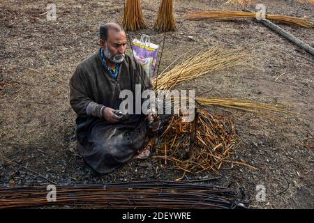 Srinagar, Indien. Dezember 2020. Ein Kashmiri Mann bereitet Zweige, um 'Kangris', (traditionelle Feuertöpfe) in Shlabugh Dorf des Bezirkes Ganderbal ungefähr 22kms von Srinagar zu bilden, Die Sommerhauptstadt von Jammu und Kaschmir.die Kangri ist ein traditioneller Feuertopf, der die Menschen während der schweren Wintermonate warm hält, wenn die Temperatur bis zu minus 20 abtaucht. Kangri ist aus Ton und Zweigen, in denen heiße Kohle gehalten wird. Kredit: SOPA Images Limited/Alamy Live Nachrichten Stockfoto