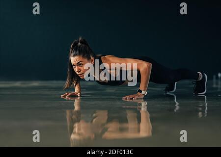 Starke Frau tun Liegestütze Übungen drinnen Stockfoto