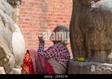 Frau raucht am Eingang zum Nyatapola Tempel (ein fünfstöckiger Pagodenstil Tempel) auf dem Taumadhi Platz (Teil des Bhaktapur Durbar Platz), UNESCO W Stockfoto