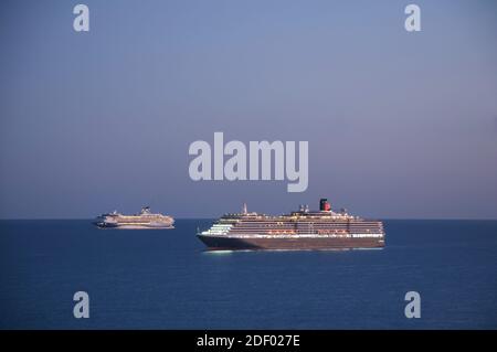 Cunard Ozeandampfer Queen Victoria und Kreuzfahrtschiff Marella Explorer ankerten in der Weymouth Bay in der Abenddämmerung. Mottballed während der Covid-19 Pandemie. Dorset. Stockfoto