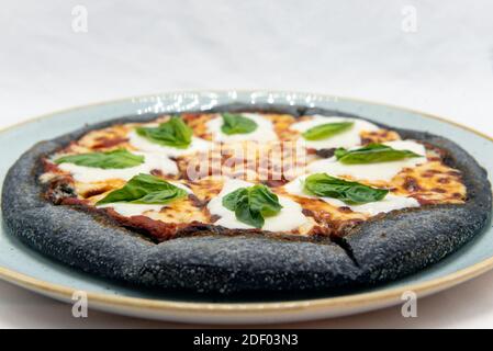 Authentisches italienisches Essen zeigt nahrhafte Margherita Black Teigpizza mit Basilikum Belag und fertig zum Essen. Stockfoto