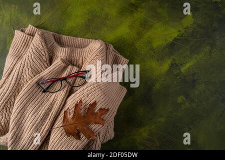 Beigefarbener Pullover auf grünem Holzhintergrund Stockfoto