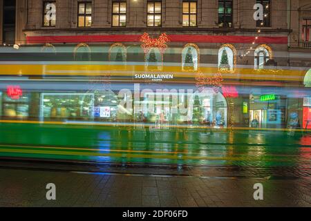 Helsinki, Finnland 30. November 2020 Stadtzentrum, historische Gebäude und eine vorbeifahrende grüne Straßenbahn. Brennende Laternen und Reflexionen nach dem Regen. Hochwertige Fotos Stockfoto