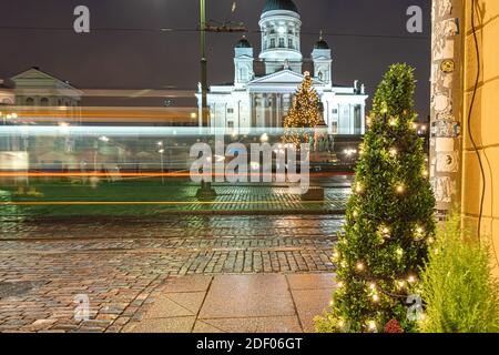 Helsinki, Finnland 30. November 2020 Stadtzentrum, historische Gebäude und eine vorbeifahrende grüne Straßenbahn. Brennende Laternen und Reflexionen nach dem Regen. Hochwertige Fotos Stockfoto