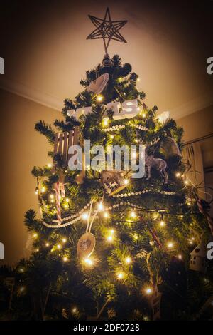 weihnachtsbaumschmuck mit funkelndem Licht und weihnachtsschmuck in Gemütliches modernes Haus mit großem Stern auf dem oberen Hintergrund Stockfoto
