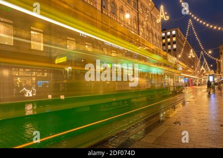 Helsinki, Finnland 30. November 2020 Stadtzentrum, historische Gebäude und eine vorbeifahrende grüne Straßenbahn. Brennende Laternen und Reflexionen nach dem Regen. Hochwertige Fotos Stockfoto