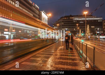 Helsinki, Finnland 30. November 2020 Stadtzentrum, historische Gebäude und eine vorbeifahrende grüne Straßenbahn. Brennende Laternen und Reflexionen nach dem Regen. Hochwertige Fotos Stockfoto