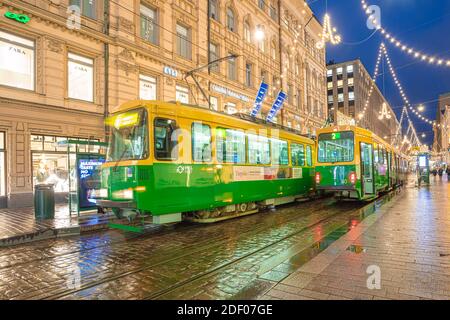 Helsinki, Finnland 30. November 2020 Stadtzentrum, historische Gebäude und eine vorbeifahrende grüne Straßenbahn. Brennende Laternen und Reflexionen nach dem Regen. Hochwertige Fotos Stockfoto