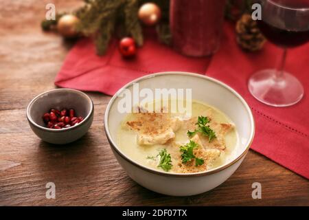 Feiertagscremesuppe mit Croutons in Sternform, Petersiliengarnitur und Granatapfelkernen, Weihnachtsdekoration und einer roten Serviette auf einem dunklen rustikalen Holzt Stockfoto