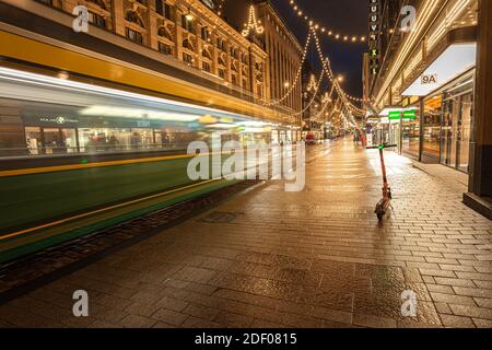 Helsinki, Finnland 30. November 2020 Stadtzentrum, historische Gebäude und eine vorbeifahrende grüne Straßenbahn. Brennende Laternen und Reflexionen nach dem Regen. Hochwertige Fotos Stockfoto