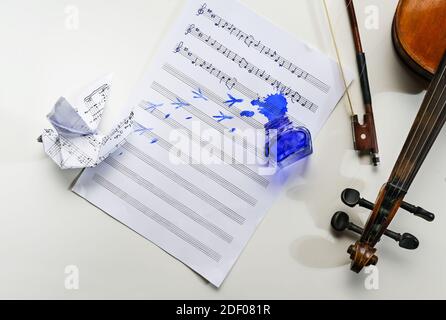 Notenblatt mit handgeschriebenem Volkslied Alle Vögel sind schon hier, umgedrehtes Tintenglas, Vogelfußabdrücke und eine Origami-Taube, Geige und Bogen auf t Stockfoto