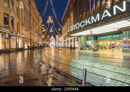 Helsinki, Finnland 30. November 2020 Stadtzentrum, historische Gebäude und eine vorbeifahrende grüne Straßenbahn. Brennende Laternen und Reflexionen nach dem Regen. Hochwertige Fotos Stockfoto