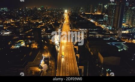 Nachts beleuchtete Stadtlandschaft mit Verkehrsautobahn im Business Center Aerial. Epische Dämmerung Stadt in Neonlicht an von Laternen Straße mit Autos beleuchtet, LKW fahren. Philippinen Hauptstadt Manila Straßen Stockfoto