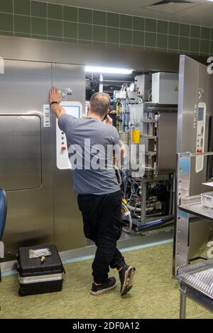 Ein Kundendienstmitarbeiter repariert einen Dampfsterilisator in einem Krankenhaus Stockfoto