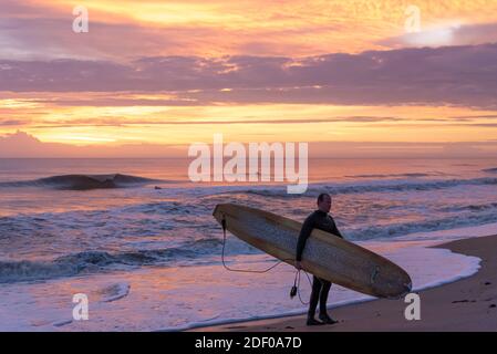 Florida Surfer mit Longboard am Strand nach einer Surf-Session vor der Morgendämmerung bei Mickler's Landing in Ponte Vedra Beach, Florida. (USA) Stockfoto