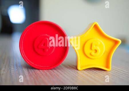 Ein Nahschuss aus einem roten Kreis und einem gelben Stern geformten Plastikspielzeug mit den Zahlen vier und fünf Stockfoto