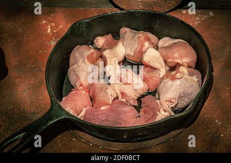 Bereiten Sie das Fleisch in einer gusseisernen Pfanne vor, die auf einem rostigen Holzofen steht. Hochwertige Fotos Stockfoto