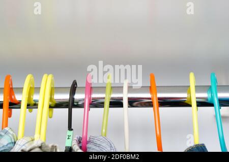 Die bunten Kunststoff-Kleiderbügel der Garderobe mit einem weißen Hintergrund Stockfoto