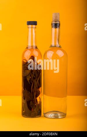 Glasflaschen mit Öl und Kräutern isoliert auf gelbem Hintergrund. Stockfoto