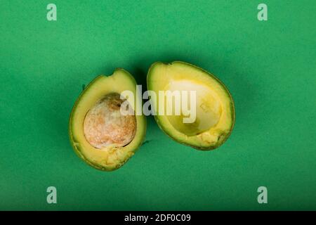 Schneiden Sie Avocado isoliert auf grünem Hintergrund Stockfoto