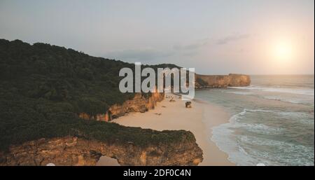 Touristenattraktion Nahaufnahme Luftaufnahme: Felswand von Batu Bolong, Bawana Strand, Sumba Insel, Indonesien. Einzigartige geologische Formation mit grünem Gras auf der Oberseite. Indonesische filmische Softlight Drohne erschossen Stockfoto