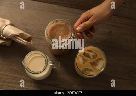 Eiskaffee in Gläsern und Milchkännchen, flach auf Holzuntergrund gelegt. Stockfoto