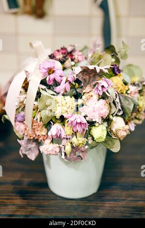 Eine Nahaufnahme einer Vase mit welkenden Blumen auf einem Holztisch Stockfoto