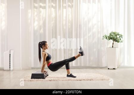 Junge Frau macht Übungen auf einem Stepper zu Hause Stockfoto