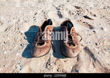 Alte Lederschuhe am Strand. Socken in Schuhen Stockfoto