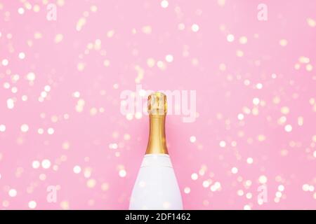 Champagner-Flasche auf rosa Hintergrund. Weihnachten, Geburtstag, Junggesellenabschied oder Hochzeitskonzept. Flache Lay-Optik. Draufsicht, Kopierbereich. Stockfoto
