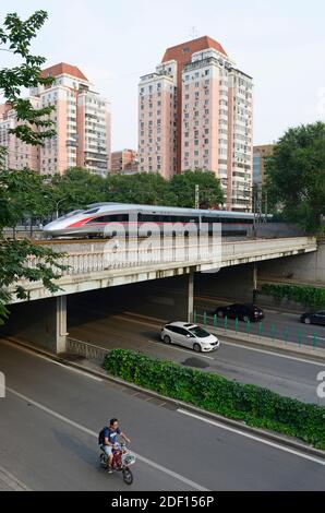 Ein Hochgeschwindigkeitszug von Fuxing überquert eine Straßenbrücke im zentralen Westen von Peking, China Stockfoto