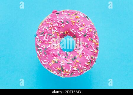 Rosa Donut Bestreut. Verglaster besprühter Donut auf blauem Hintergrund. Draufsicht, Kopierbereich. Stockfoto