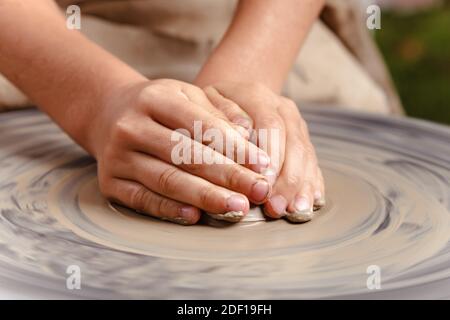 Rotierendes Töpferrad und Tonwaren darauf von oben genommen. A modelliert seine Hände mit einem Tonbecher auf einem Töpferrad. Hände in Ton. Prozess von. Stockfoto