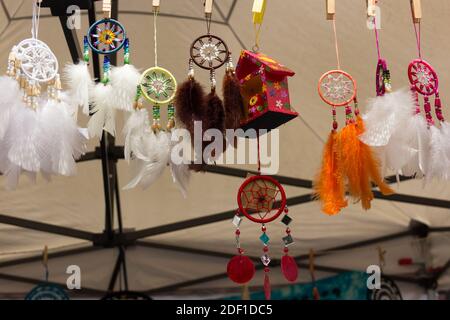 White feather dreamcatchers hanging in street market kiosk. Handmade souvenirs, original design concepts Stock Photo