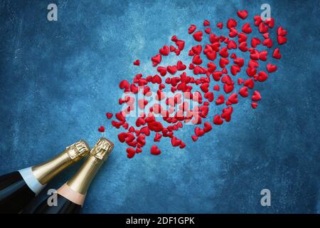 Valentinstag Hintergrund. Zwei Champagnerflaschen mit roten Herzen auf blauem Hintergrund. Platz kopieren, Draufsicht. Flaches Lay of Valentines Day Feier Stockfoto