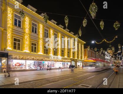 Graz, Österreich - 22. November 2019: Straßenbahn fährt vorbei und wunderschöne Weihnachtsdekorationen auf der berühmten Herrengasse, nachts, im Stadtzentrum von Graz Stockfoto