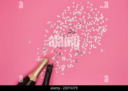 Champagner-Flasche mit Konfetti-Sternen auf rosa Hintergrund. Flat Lay of Christmas, Jubiläum, Bachelorette, Neujahr Feier Konzept. Platz kopieren, t Stockfoto