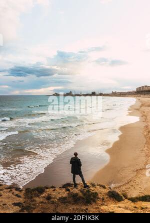 Blick auf EINEN Mann von hinten mit Blick auf EINEN Strand In EINEM wolkigen Himmel Stockfoto